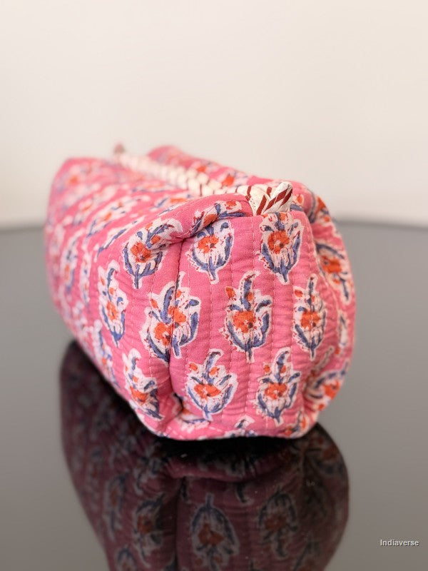 Pink fabric pouch with floral pattern on a reflective surface