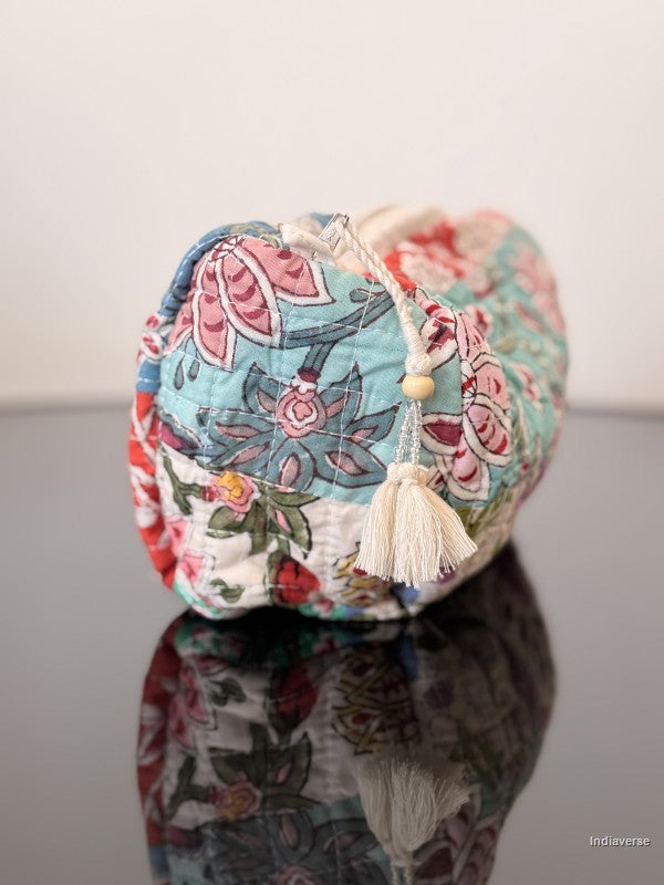 Colorful floral-patterned fabric pouch on a reflective surface with a white background