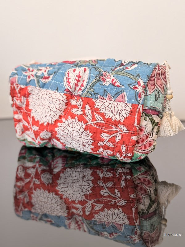 Floral-patterned fabric pouch with tassels on a reflective surface