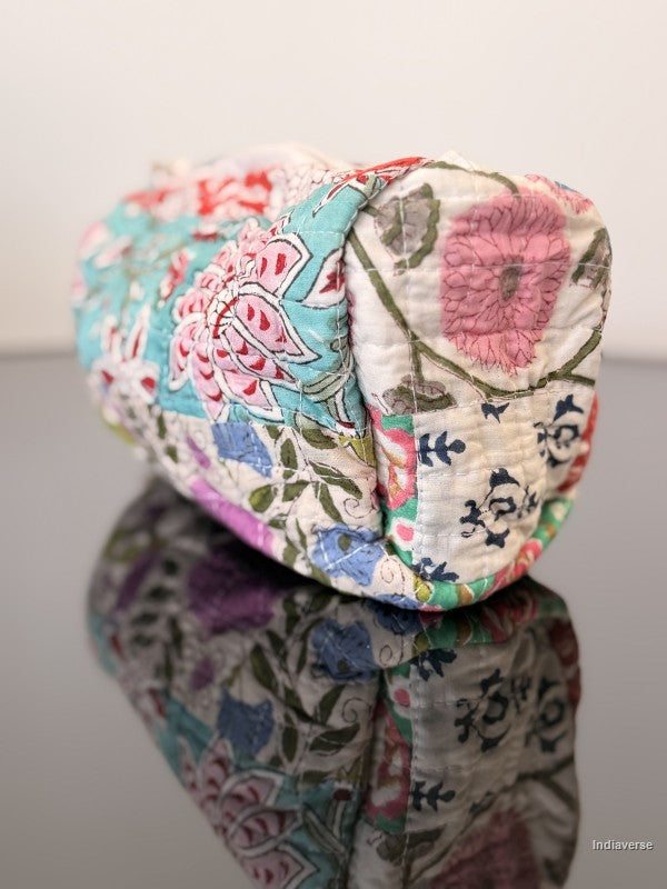 Colorful floral-patterned fabric pouch on a reflective surface with a white background