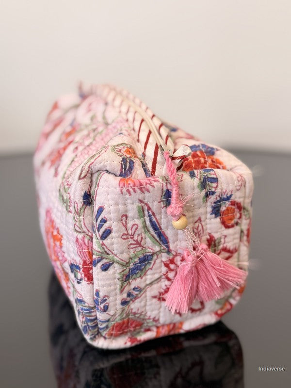toiletry pouch with tassel and floral pattern sitting on a glass surface