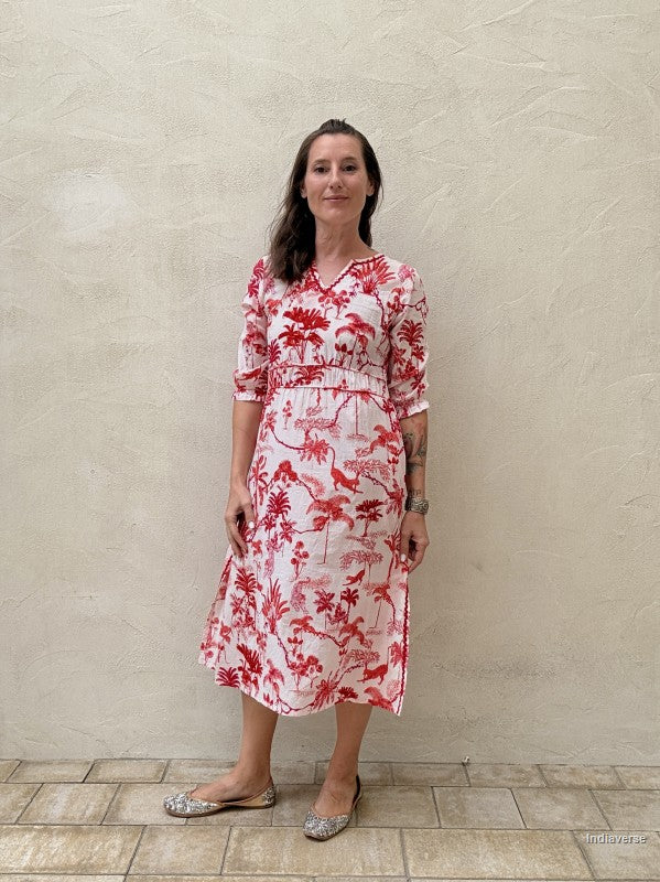 Woman wearing a red and white floral dress against a beige wall.