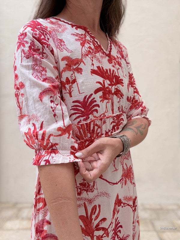 Person wearing a red and white floral dress with a neutral background