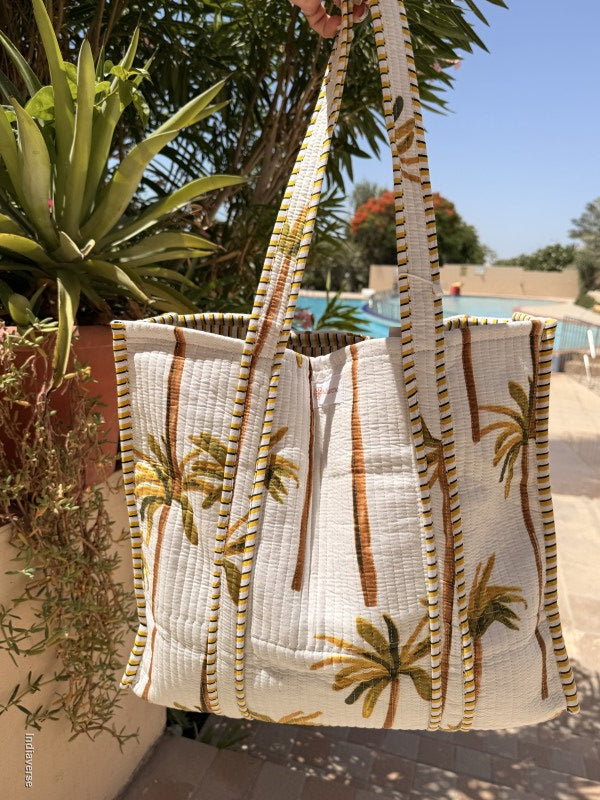 Textile with palm tree design held up against a blurred outdoor background