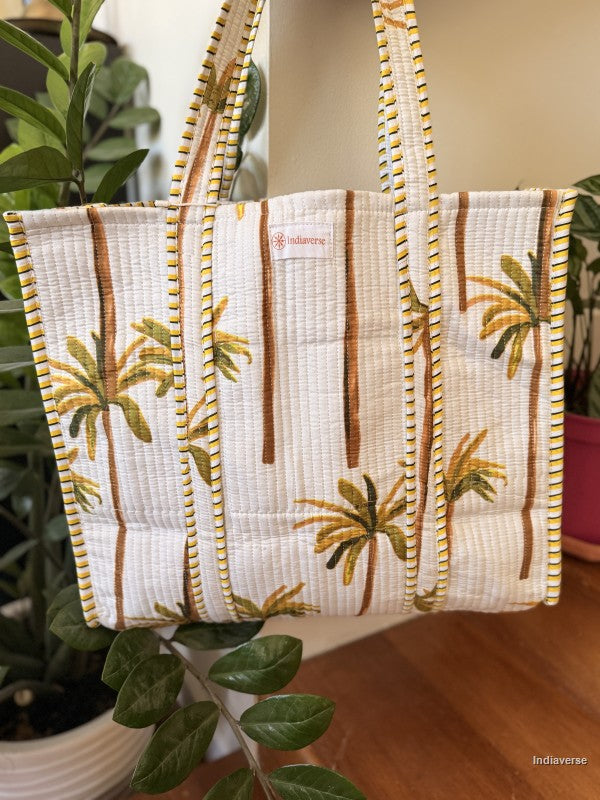 Tote bag with palm tree design on a mannequin against a plant background