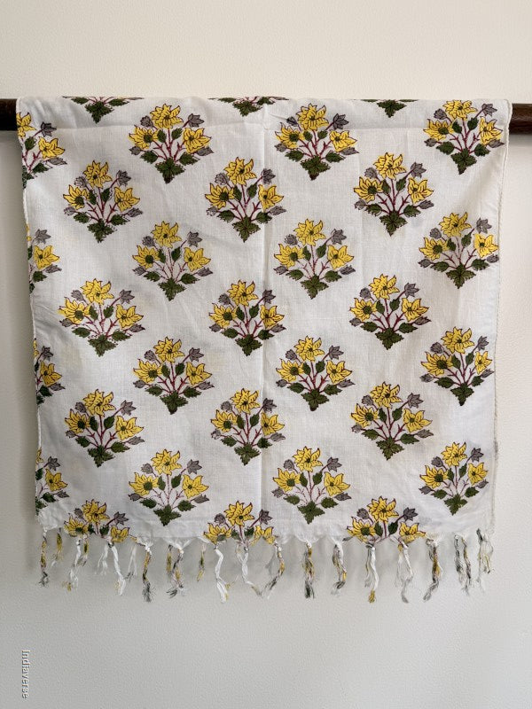 cotton scarf with geometric yellow flower design hanging from a wooden beam