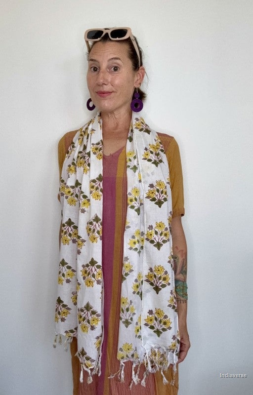 woman wearing a cotton scarf with yellow flowers standing in front of a white wall