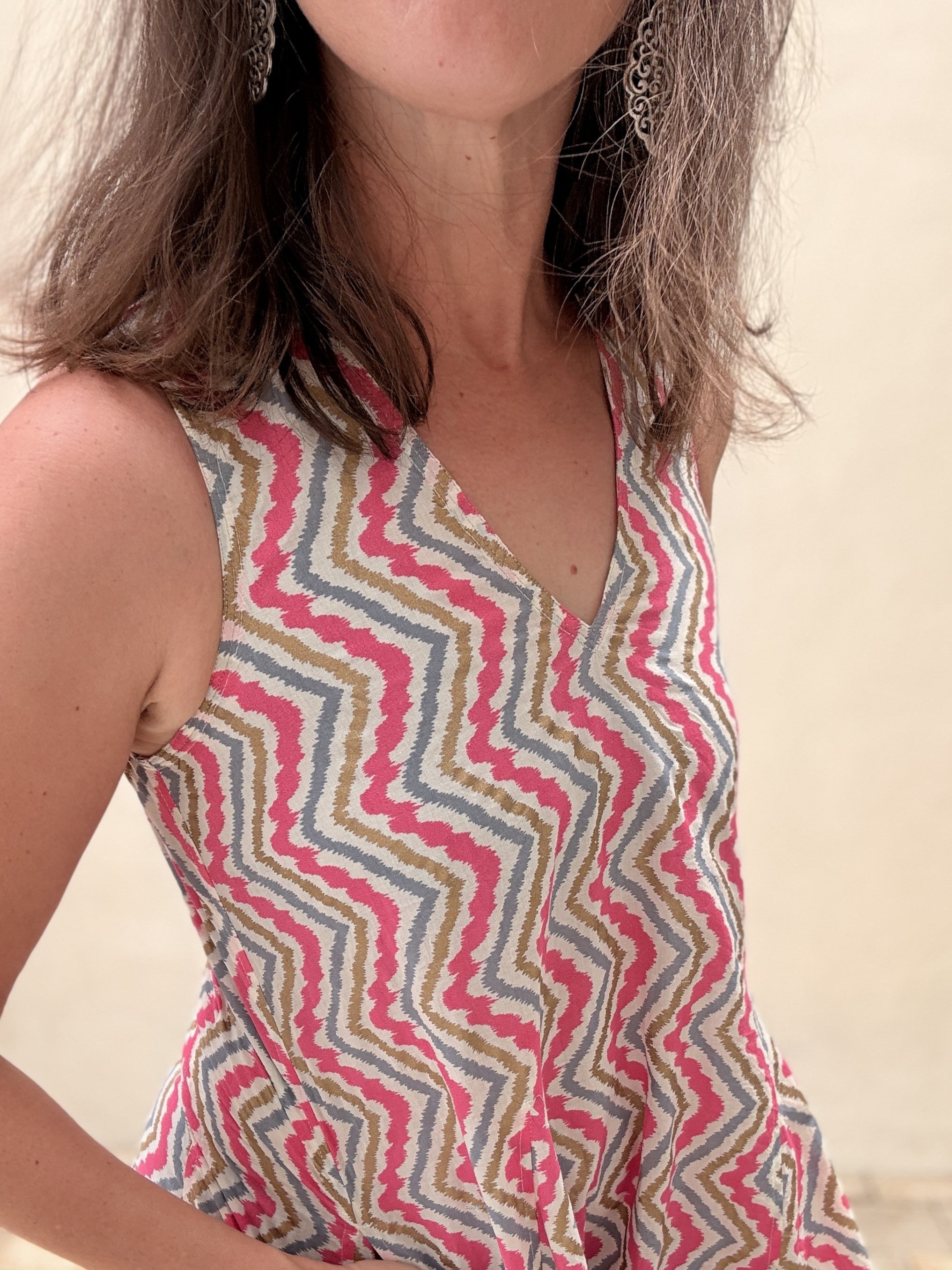 Person wearing a sleeveless dress with a colorful zigzag pattern on a blurred background