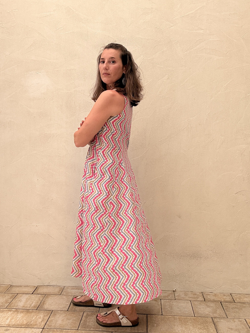 Woman wearing a red and white zigzag patterned dress against a beige wall.