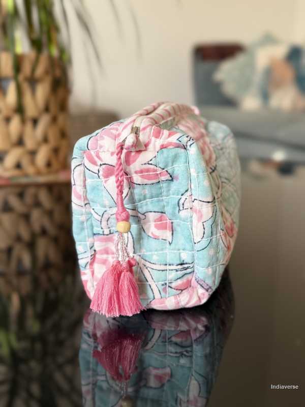baby blue toiletry bag with pink lotus flowers sitting in a glass table in the living room | Aqua Lotus