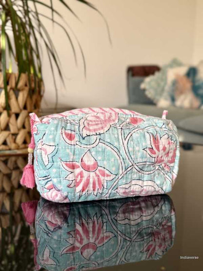 baby blue toiletry bag with pink lotus flowers sitting in a glass table in the living room | Aqua Lotus