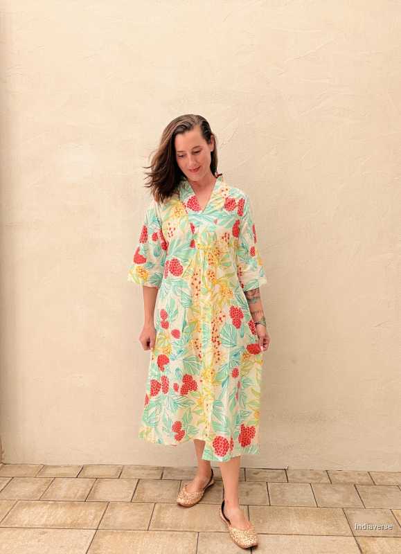 woman standing in front of a beige wall wearing a midi size summer dress