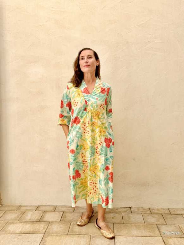 woman standing in front of a beige wall wearing a midi size summer dress