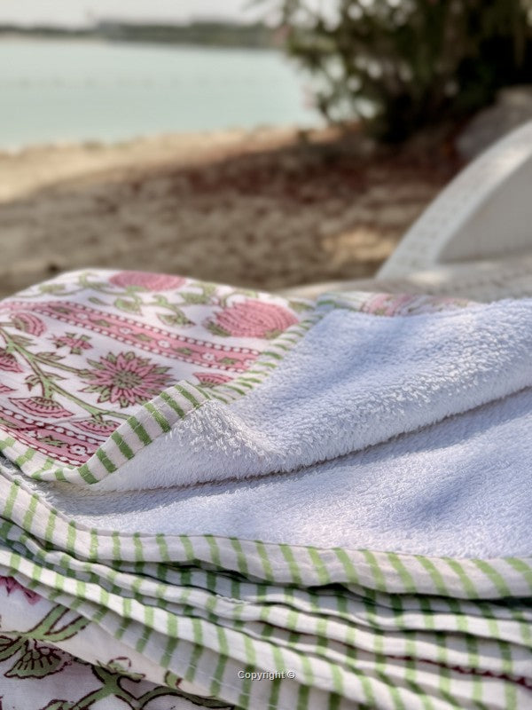 Stack of folded towels with floral and checkered patterns on a blurred outdoor background