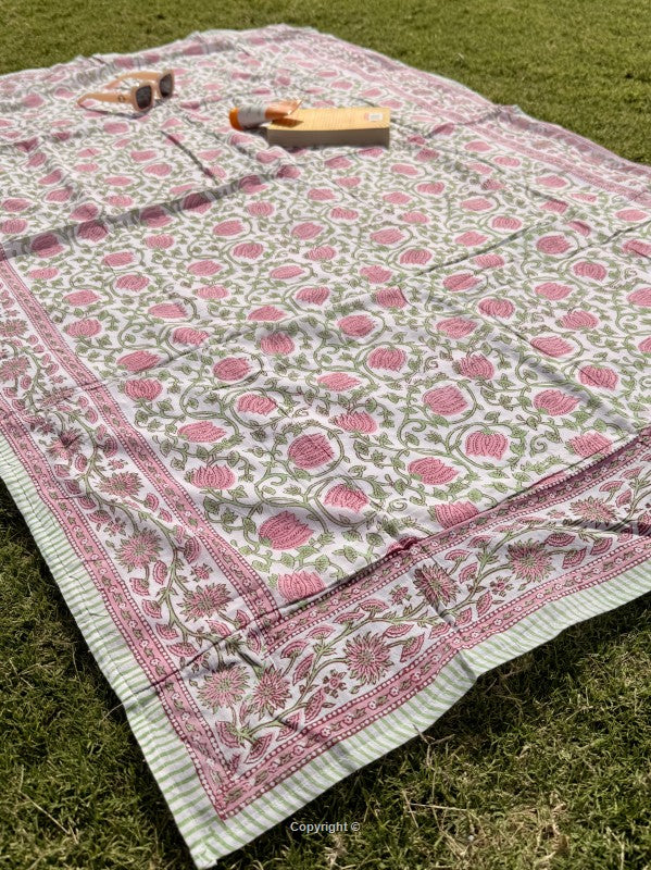 Decorative quilt with pink floral pattern on grass