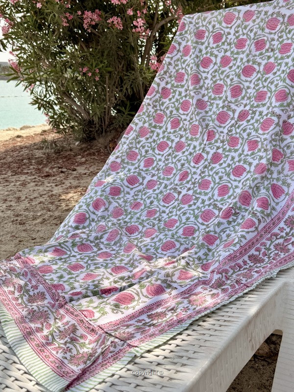 Pink and white patterned fabric draped over a chair by a body of water.