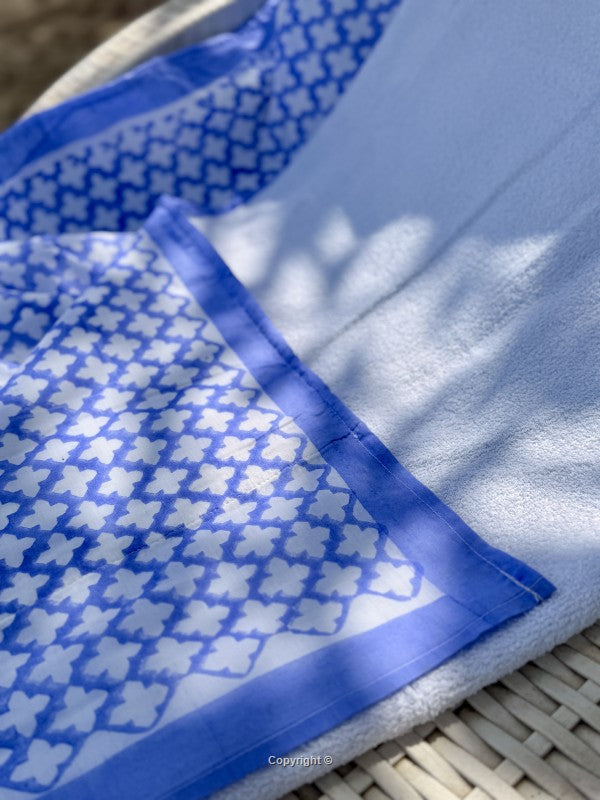 Blue and white patterned towel on a woven surface