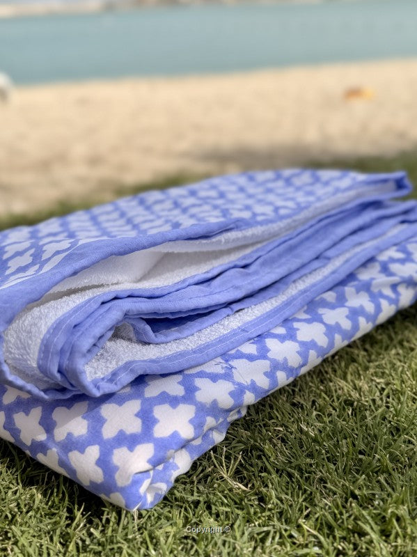 Folded blue blanket with white patterns on grass