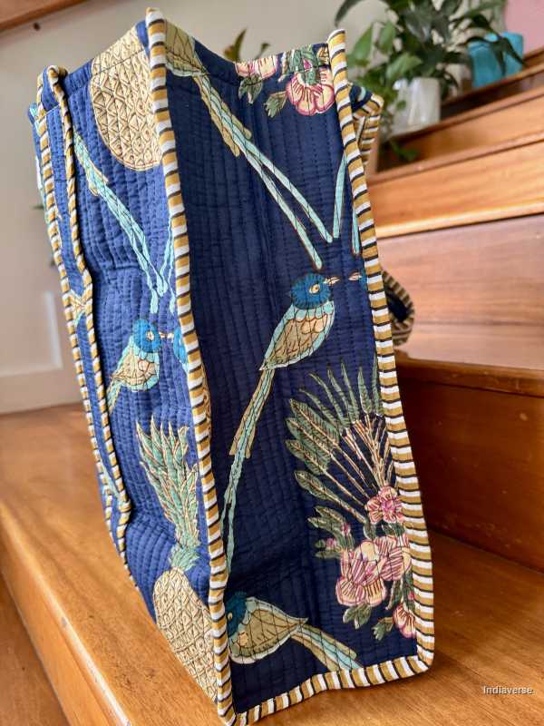 tropical royal blue tote bag with bird and pineapple design standing on wooden floor