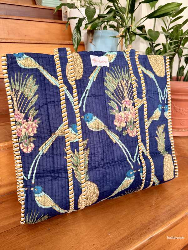 tropical royal blue tote bag with bird and pineapple design standing on wooden floor