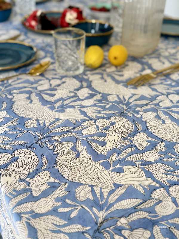 Tablecloth with bird pattern on a table setting with lemons and glasses.