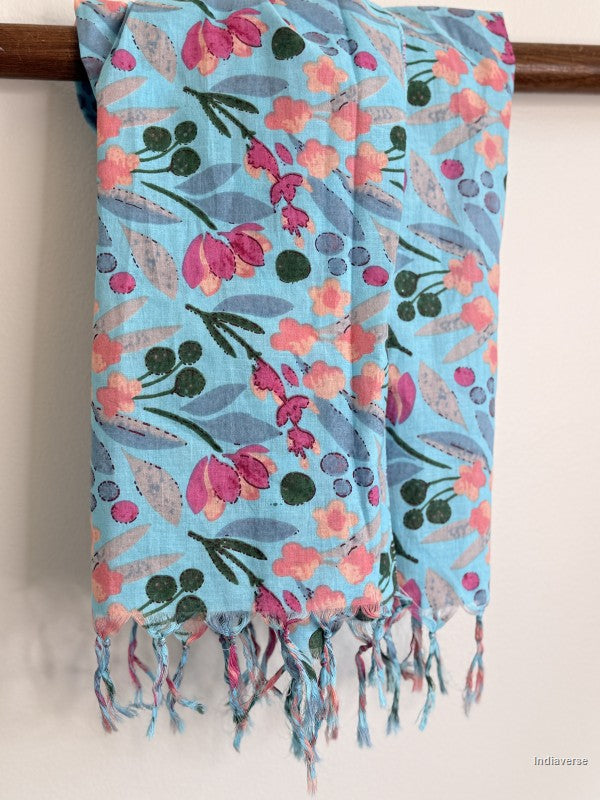 close up of blue floral scarf with tassels hanging from a wooden beam