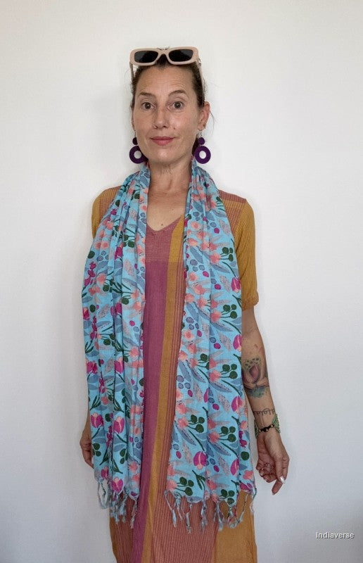 woman wearing a blue floral cotton scarf standing in front of a white wall
