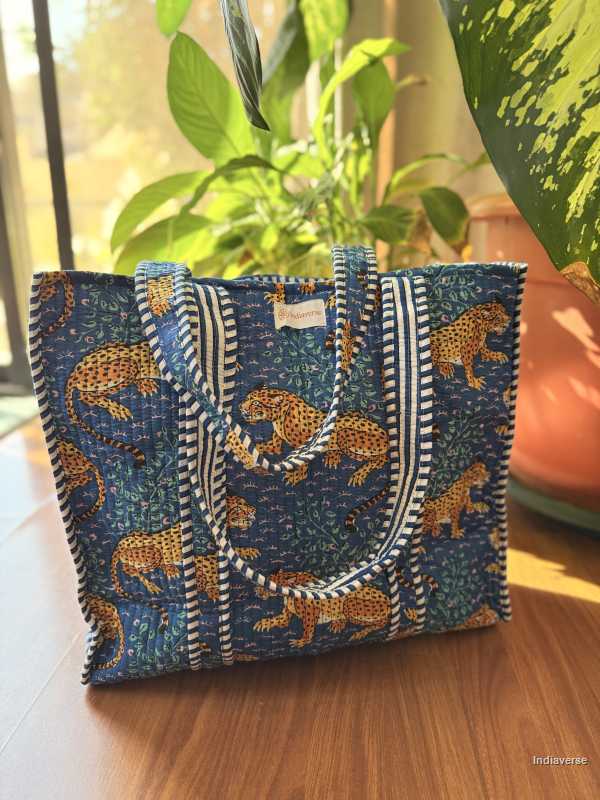 Blue patterned bag with leopards on a wooden surface with plants in the background