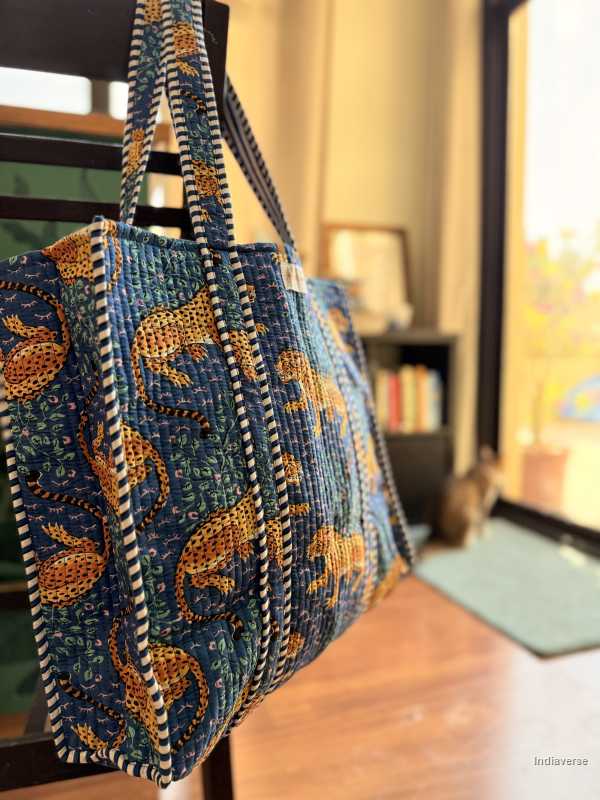 Blue embroidered bag with gold patterns on a wooden surface