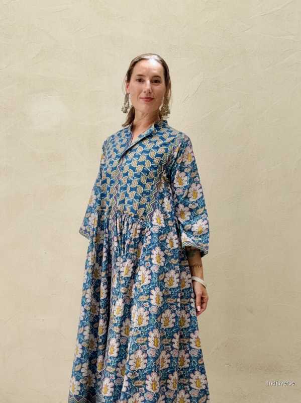 Woman wearing a blue floral dress against a beige wall