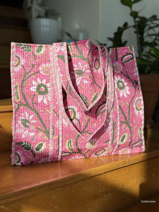 Pink floral-patterned bag on a wooden surface with plants in the background