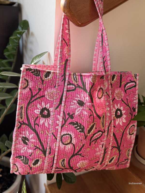 Pink tote bag with floral pattern held by a person indoors