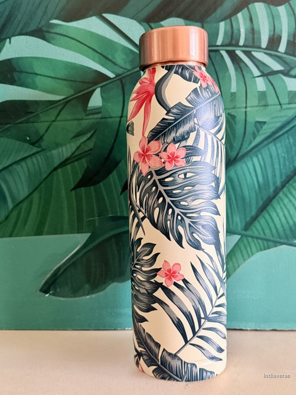 copper water bottle with tropical leaf and birds of paradise design standing in front of a green leaf wallpaper