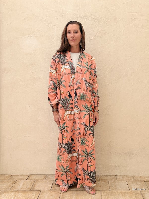 Woman wearing a long, patterned dress against a beige wall.