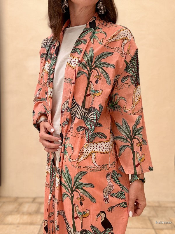 Woman wearing a pink patterned kimono-style jacket with a neutral background