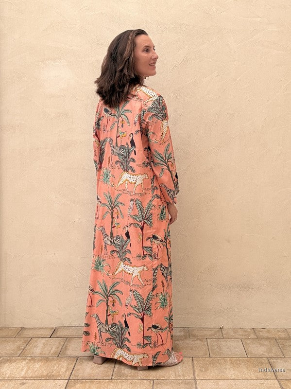 Woman wearing a long, patterned dress against a beige wall.