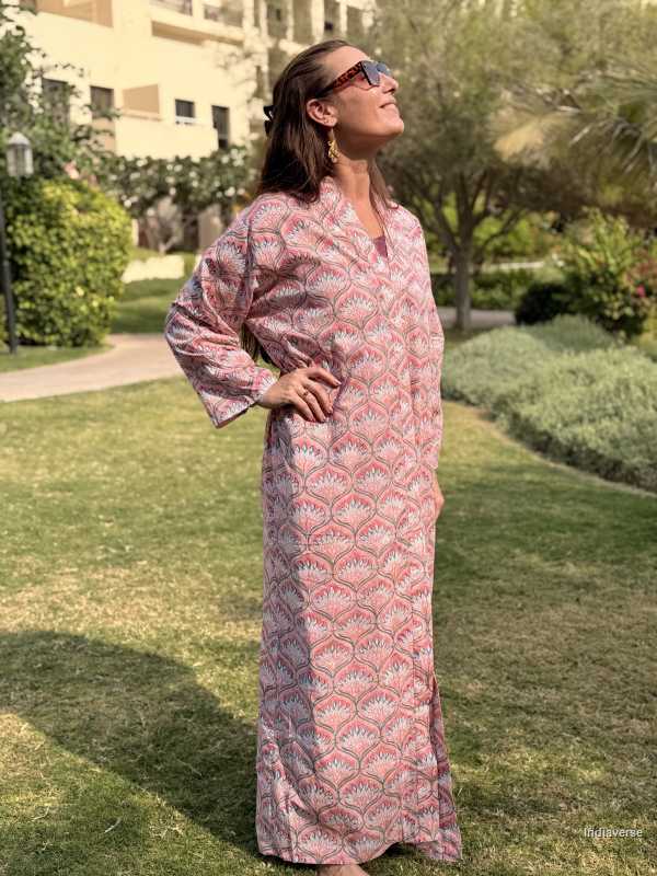 Woman in a pink patterned dress standing outdoors on grass