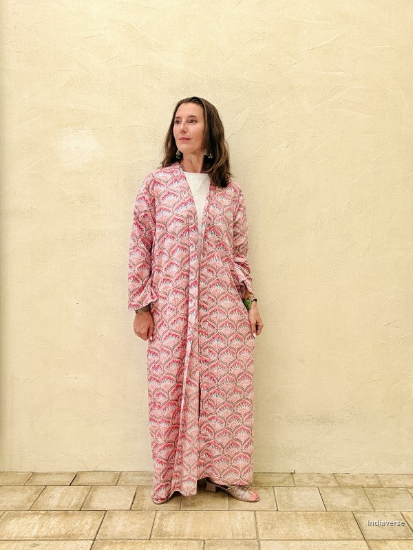woman wearing a long abaya robe with symmetric lotus pattern against a beige wall