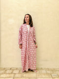 woman wearing a long abaya robe with symmetric lotus pattern against a beige wall