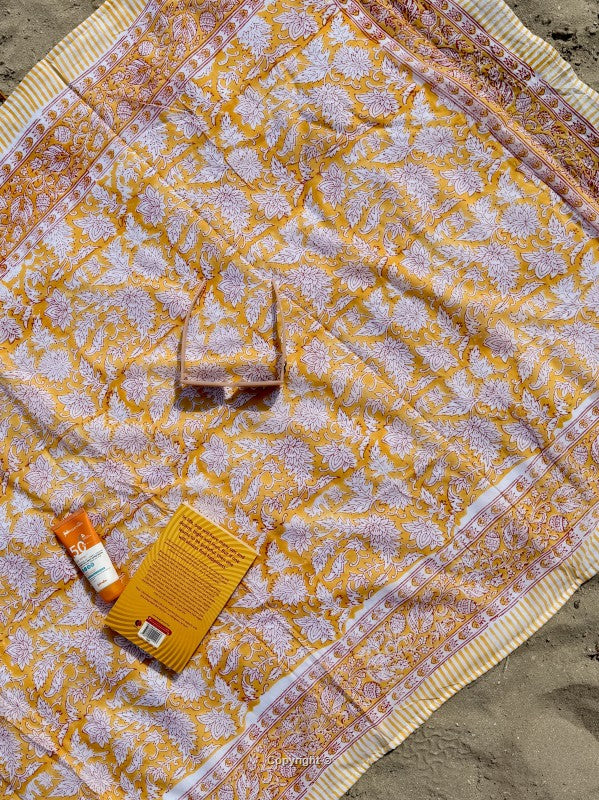 Patterned fabric with a small box and bottle on a sandy surface