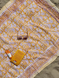 Patterned fabric with a small box and bottle on a sandy surface