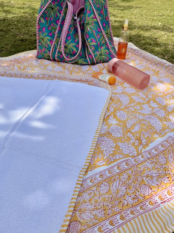 Colorful bag and bottles on a patterned blanket outdoors