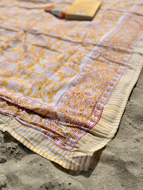 Yellow and white patterned fabric on a sandy surface