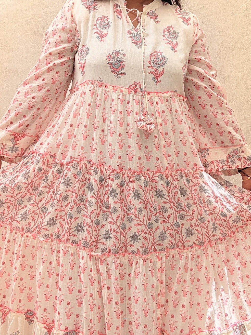 Floral patterned dress with long sleeves and a flowing skirt on a plain background