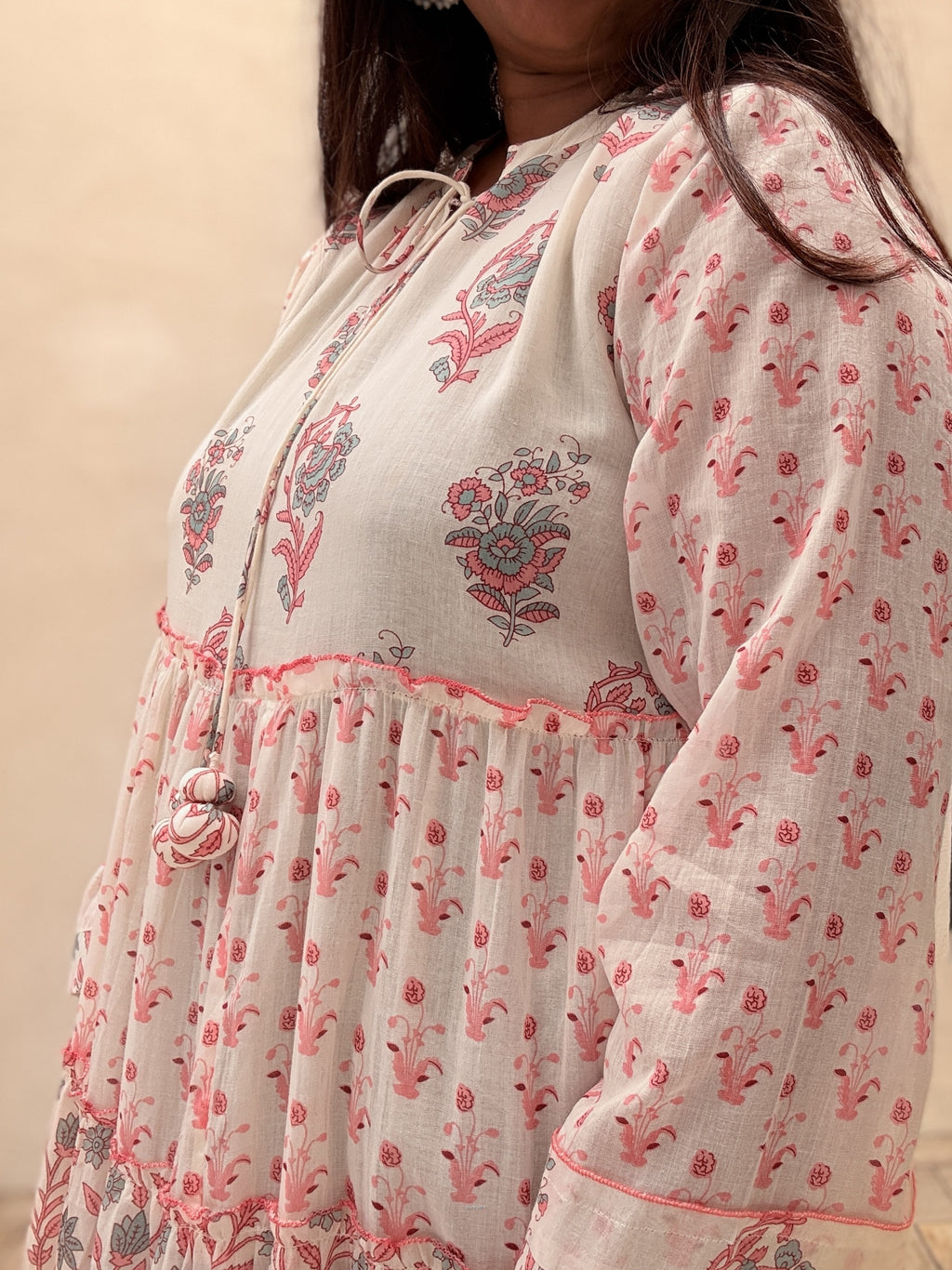 Woman wearing a floral dress with intricate embroidery on a beige background