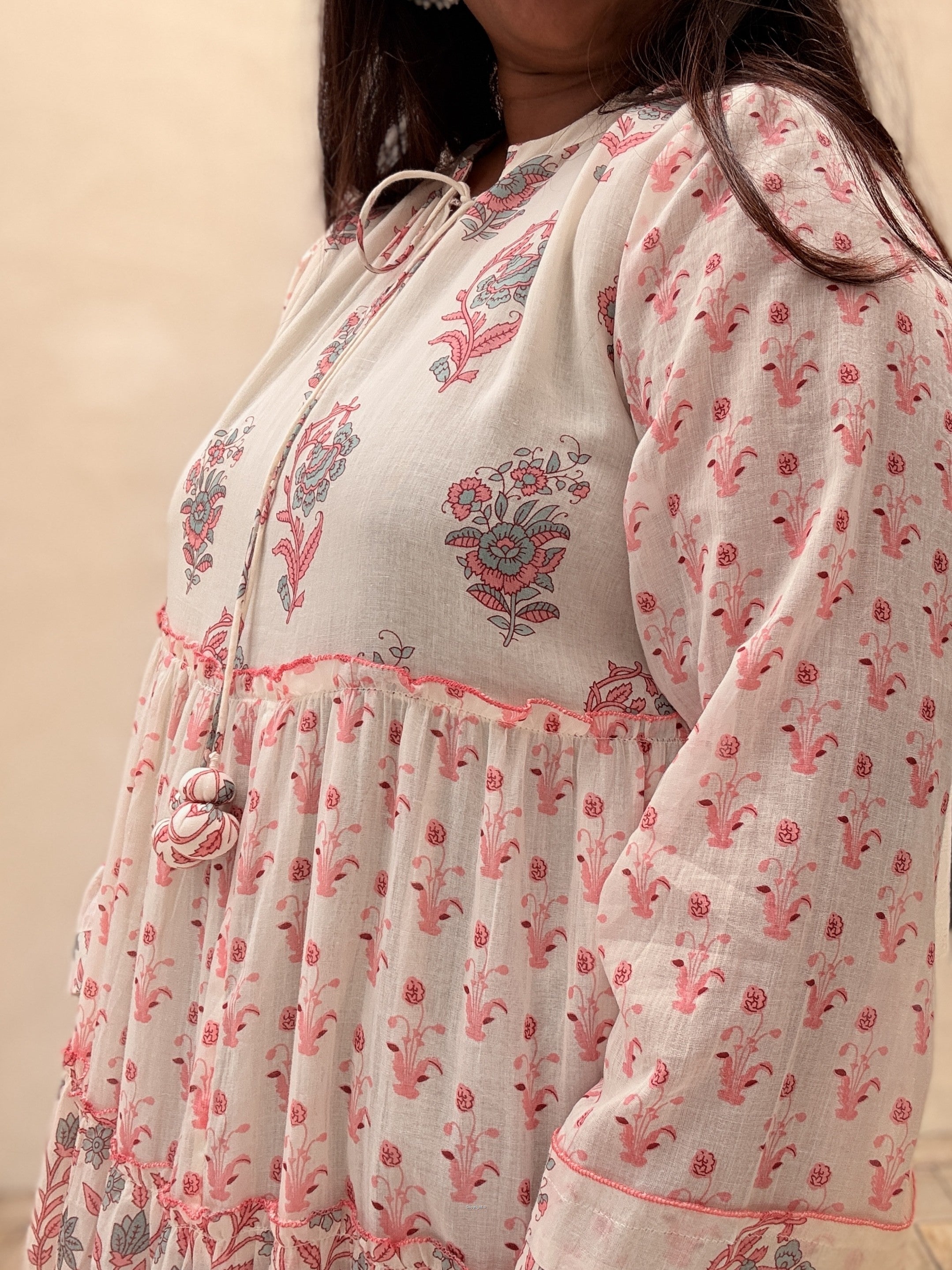 Woman wearing a floral dress with intricate embroidery on a beige background