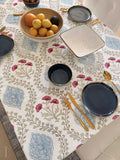 Table setting with ceramic plates, bowls, and cutlery on a patterned tablecloth.