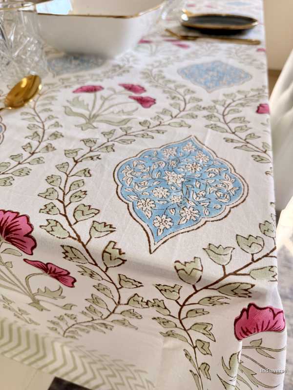 Floral and geometric patterned tablecloth on a table with a white bowl and gold decorative item.