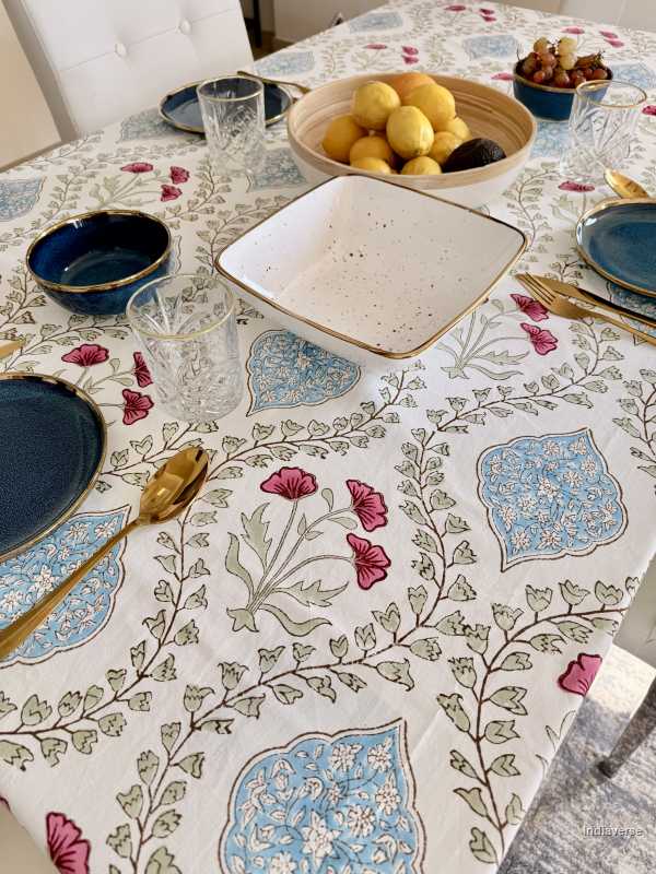 Table setting with a floral tablecloth, plates, and glasses.