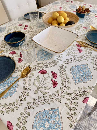 Table setting with a floral tablecloth, plates, and glasses.